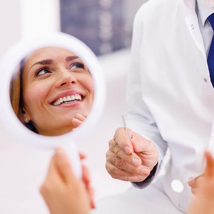 Woman smiling in reflection of handheld mirror