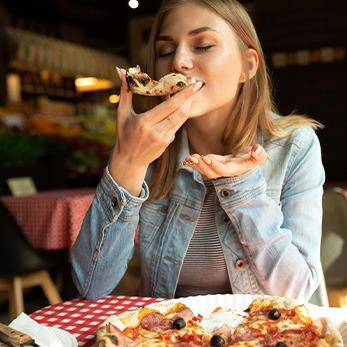 Woman enjoying slice of pizza in restaurant