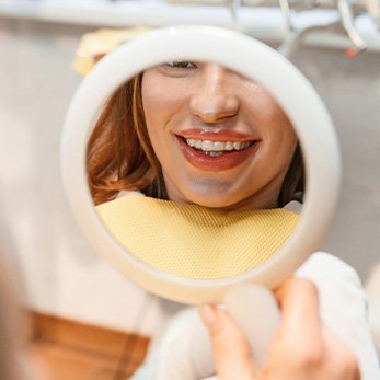 Patient with clear aligners smiling at reflection in mirror