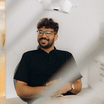 Patient with black glasses smiling in treatment chair
