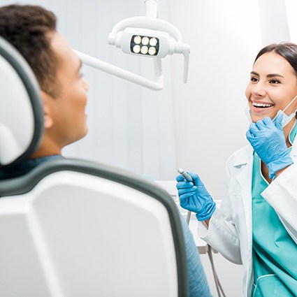 Smiling dentist looking at patient in treatment chair