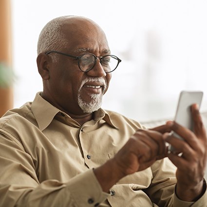 Senior man looking at phone on couch