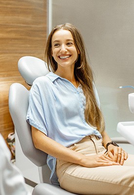 Woman in treatment chair smiling at dentist