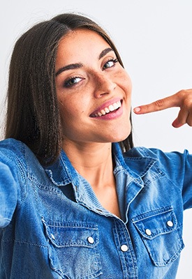 Smiling woman pointing to her white teeth