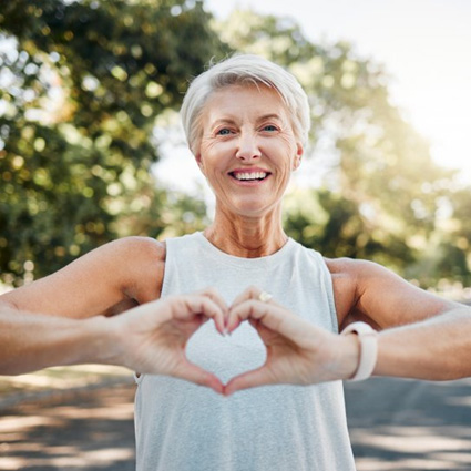 Lady smiles while making shape of heart with her hands