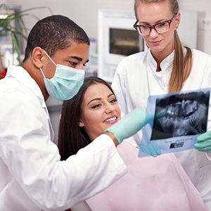 Patient smiling as dentist looks at X-ray