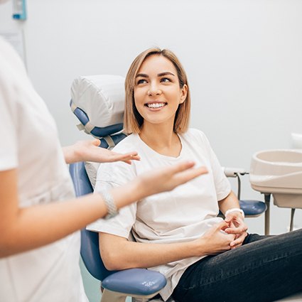 An obscured dentist talking to her smilng patient