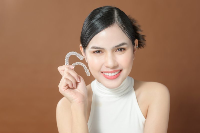 Lady smiles while showing off Invisalign clear aligners