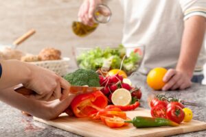 People preparing healthy foods (slicing fruit and veggies).